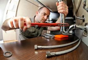 Plumber in Antelope CA tightens sink drain with a pipe wrench